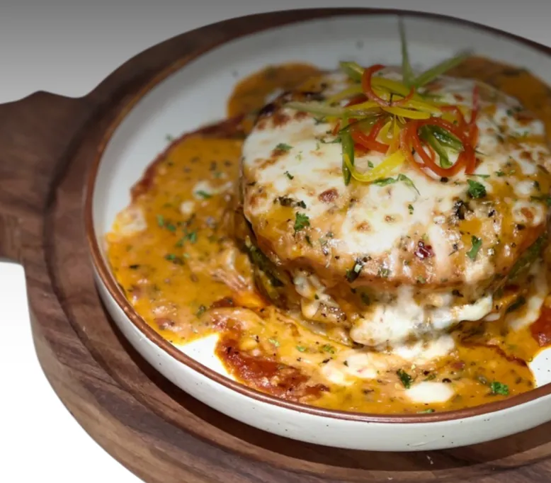 Roasted vegetable lasagna under molten cheese in a herbed tomato-cream sauce