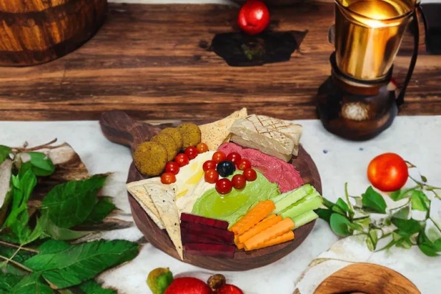 Hummus platter with falafel, pita, crudités and beet hummus on a wooden board