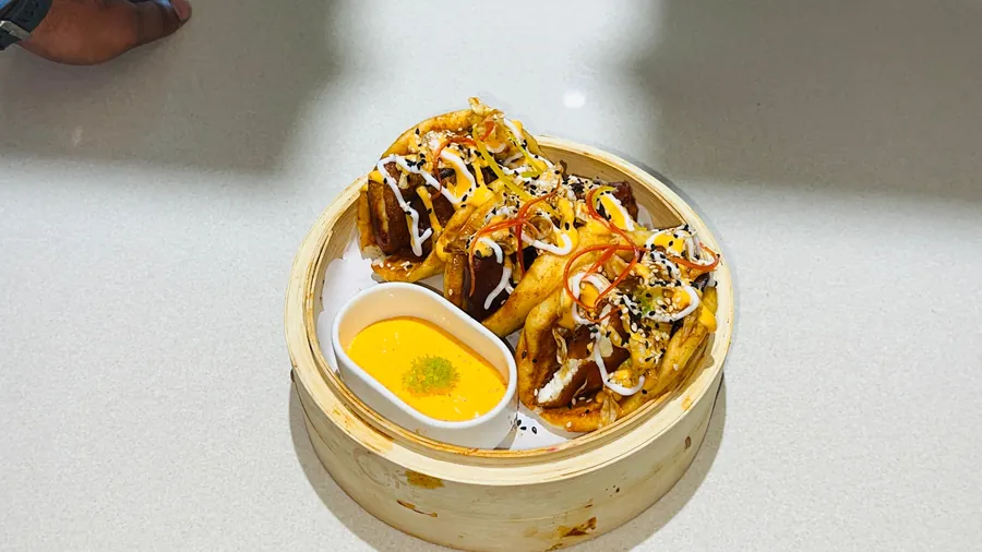 Korean crispy cottage cheese bao in a bamboo steamer with spicy mayo