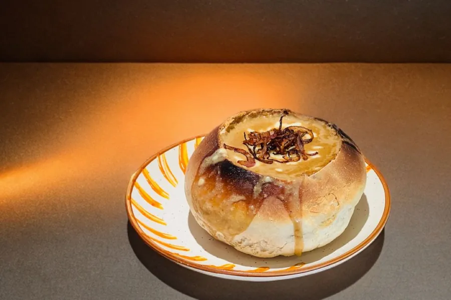 French onion soup baked inside a bread bowl, topped with crisp onions